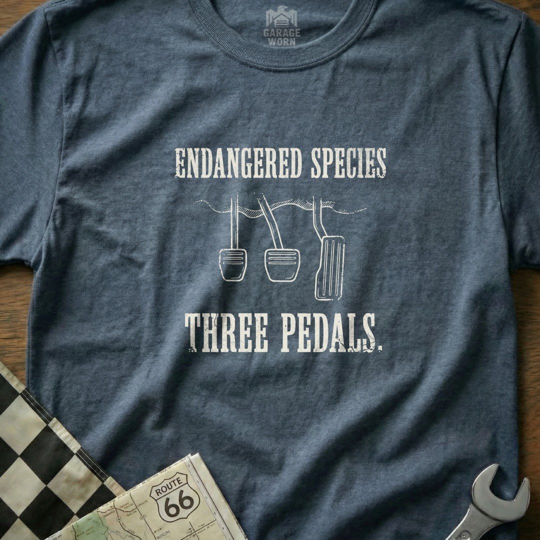 T-shirt with text "Endangered Species Three Pedals" over a checkered flag and map.