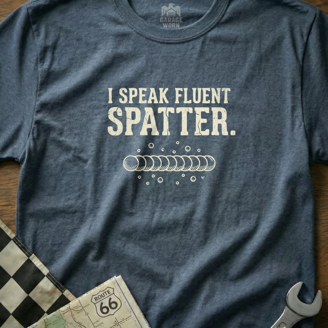 Blue t-shirt with white text reading "I SPEAK FLUENT SPLATTER" and a row of bubbles.