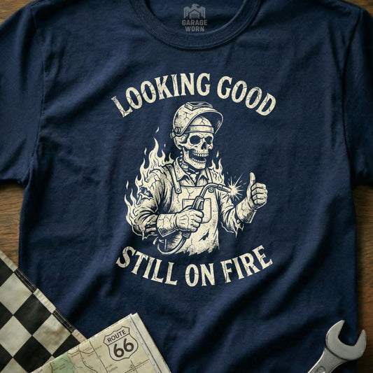 Navy t-shirt with skeleton welder giving thumbs up, "Looking Good Still On Fire".