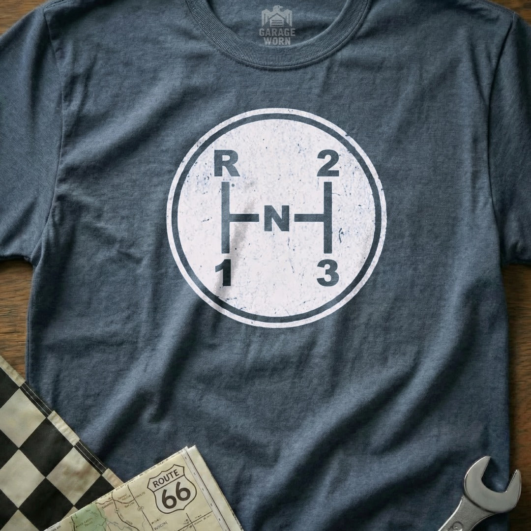 Dark grey t-shirt with distressed manual transmission shift pattern graphic and "Garage Worn" logo.