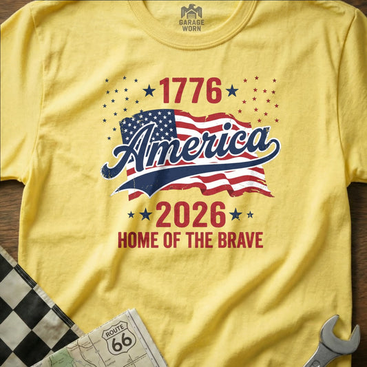 Yellow t-shirt with "America 1776-2026 Home of the Brave" and American flag graphic.