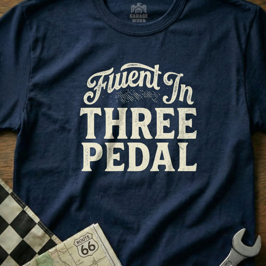 Navy t-shirt with "Fluent In THREE PEDAL" text, checkered flag, and map.