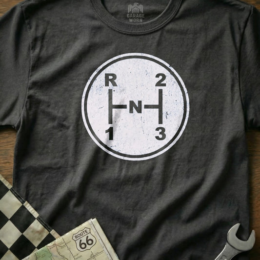Grey t-shirt with a white manual transmission shift pattern graphic and the word "Garage Worn".