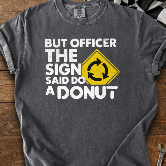 Dark gray t-shirt with white text and yellow roundabout sign reading "BUT OFFICER THE SIGN SAID DO A DONUT".