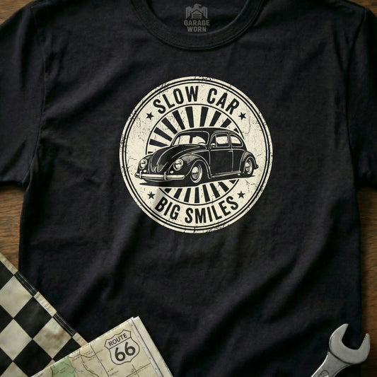 Black t-shirt with a circular graphic of a Volkswagen Beetle and text "Slow Car Big Smiles".