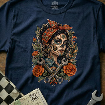 Tattoo style graphic of a woman with sugar skull makeup and wrenches on a navy t-shirt.
