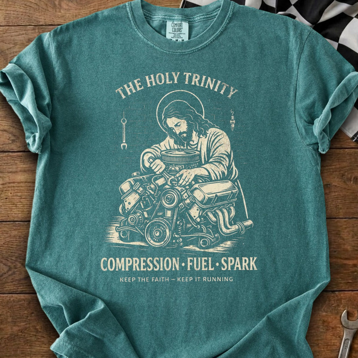 Jesus working on an engine, with text "The Holy Trinity Compression Fuel Spark Keep the Faith - Keep It Running".