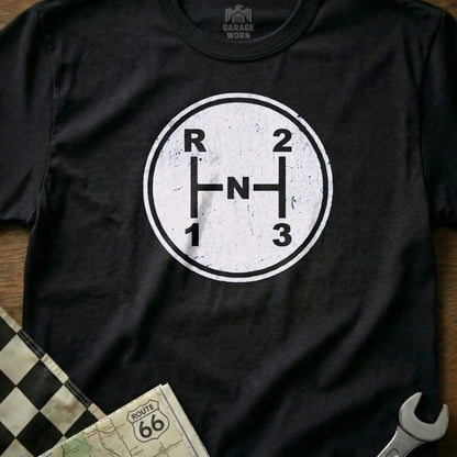 Black t-shirt with white manual transmission shift pattern graphic and "GARAGE WORN" logo.