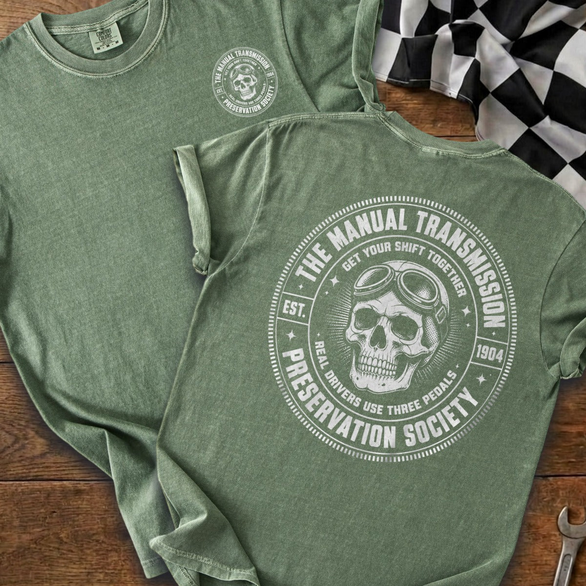 Green tee with skull, goggles, and "The Manual Transmission Preservation Society" text.