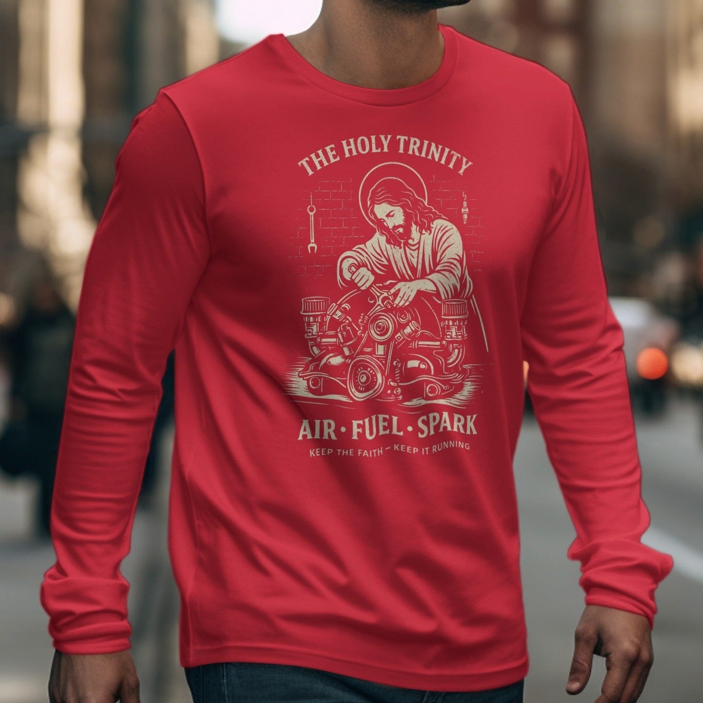 Red long-sleeve shirt with Jesus working on an engine graphic and "The Holy Trinity Air Fuel Spark" text.