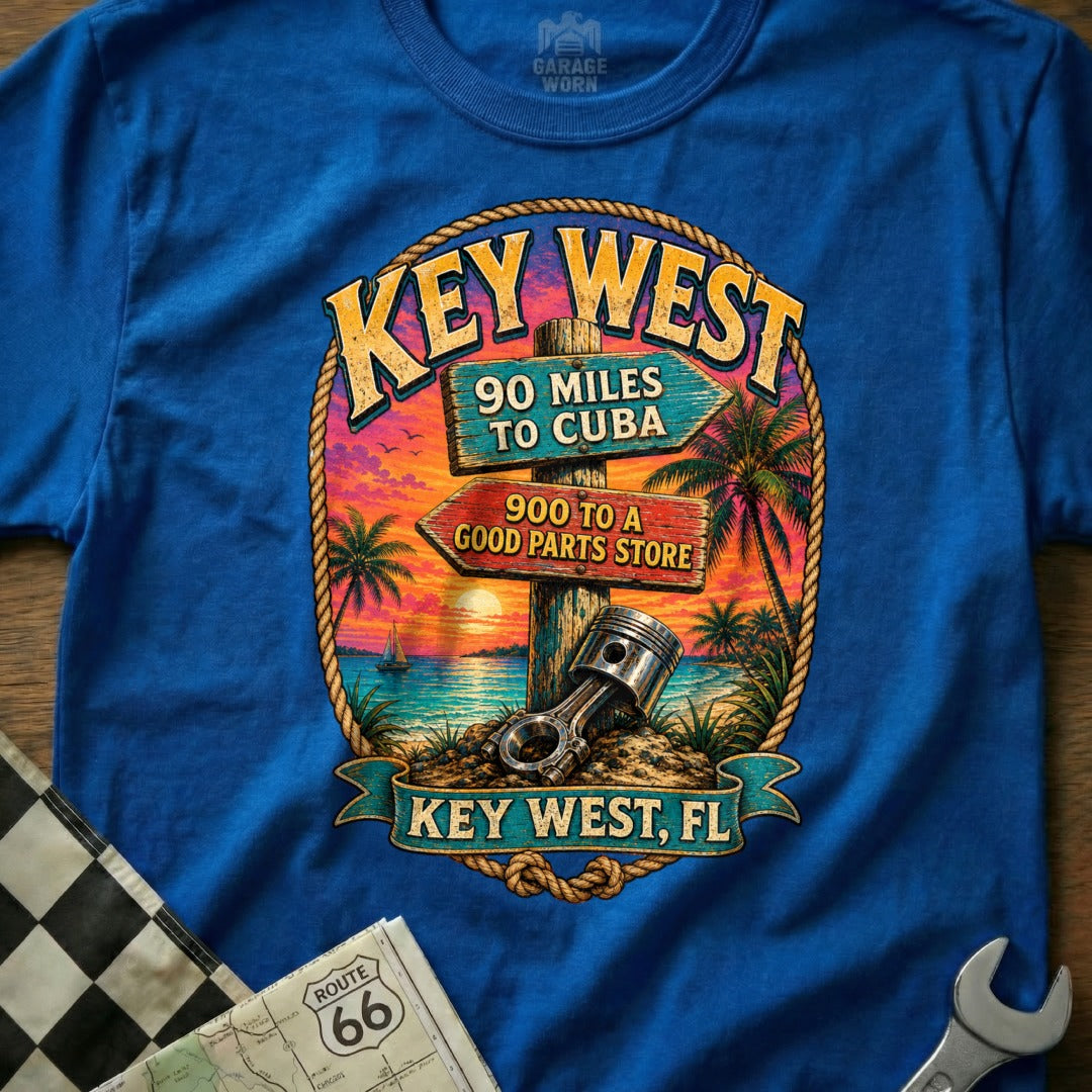 Blue t-shirt with Key West sunset graphic featuring directional signs and an engine piston.