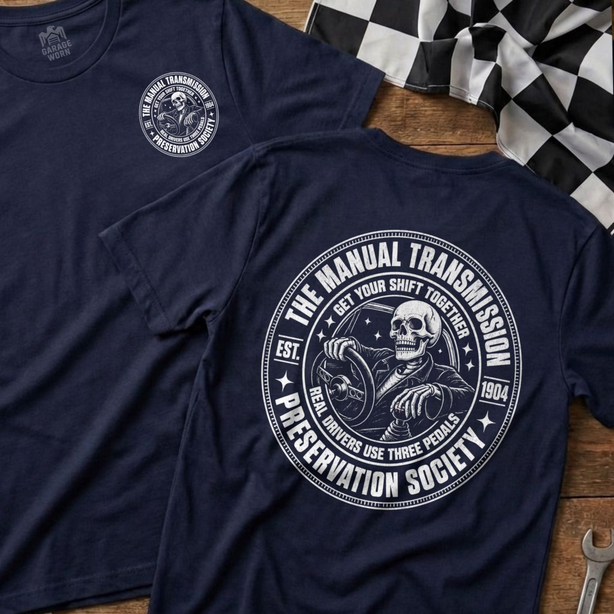 Navy t-shirt with a circular graphic of a skeleton driving, "The Manual Transmission Preservation Society" text.