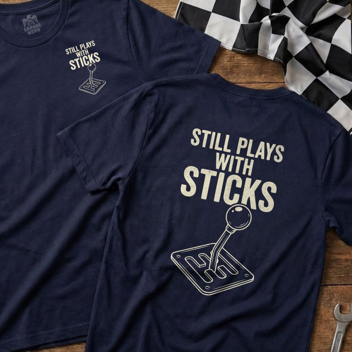 Navy t-shirt with "Still Plays With Sticks" and a gear shifter graphic.