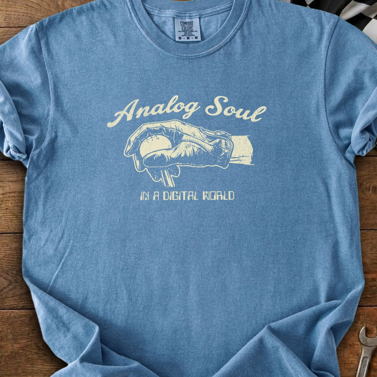 Blue t-shirt with cream graphic of hand holding baseball and text "Analog Soul IN A DIGITAL WORLD".