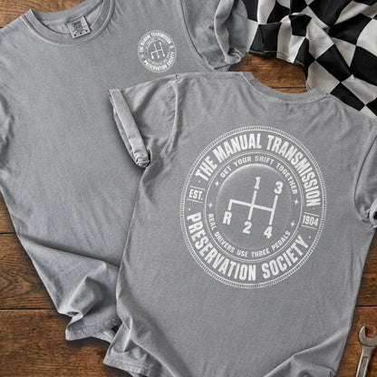 Grey t-shirts featuring a graphic of manual transmission stick shift and text.