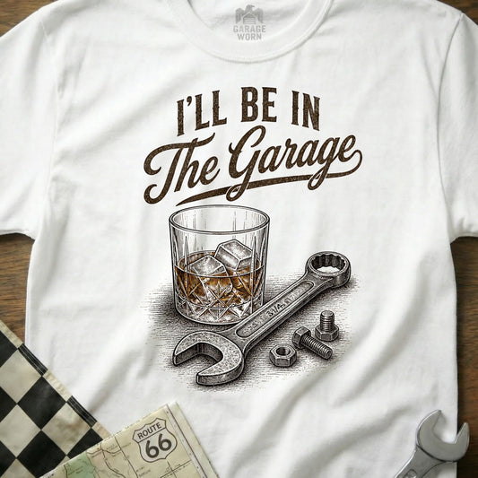 White t-shirt with "I'll Be In The Garage" text over a glass of whiskey and a wrench.
