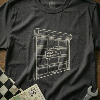 Dark t-shirt with sketch of garage door and "Knock First, Bring Coffee" sign.