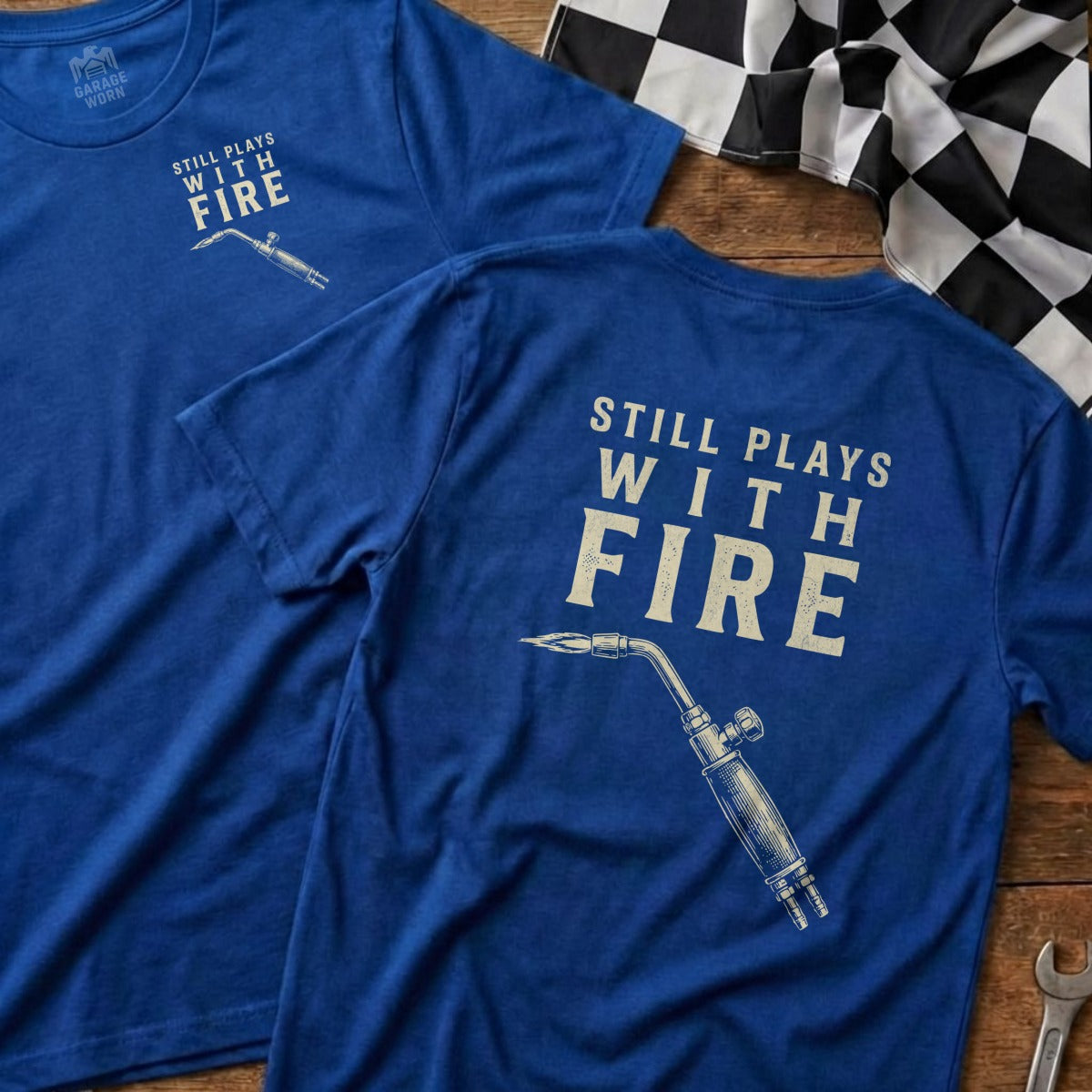 Blue t-shirt with "Still Plays With Fire" and torch graphic.