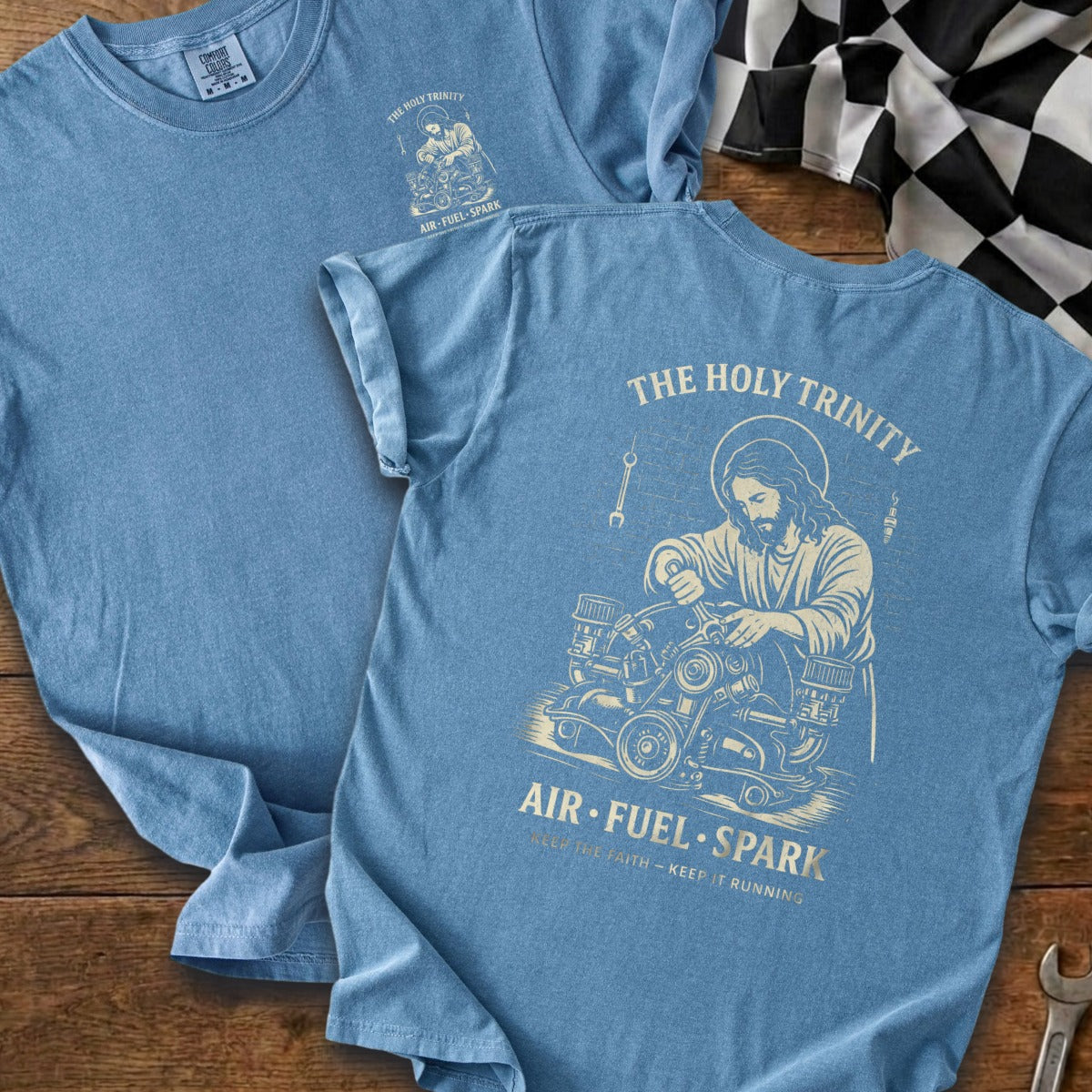Blue t-shirt with "The Holy Trinity" graphic of Jesus working on an engine.