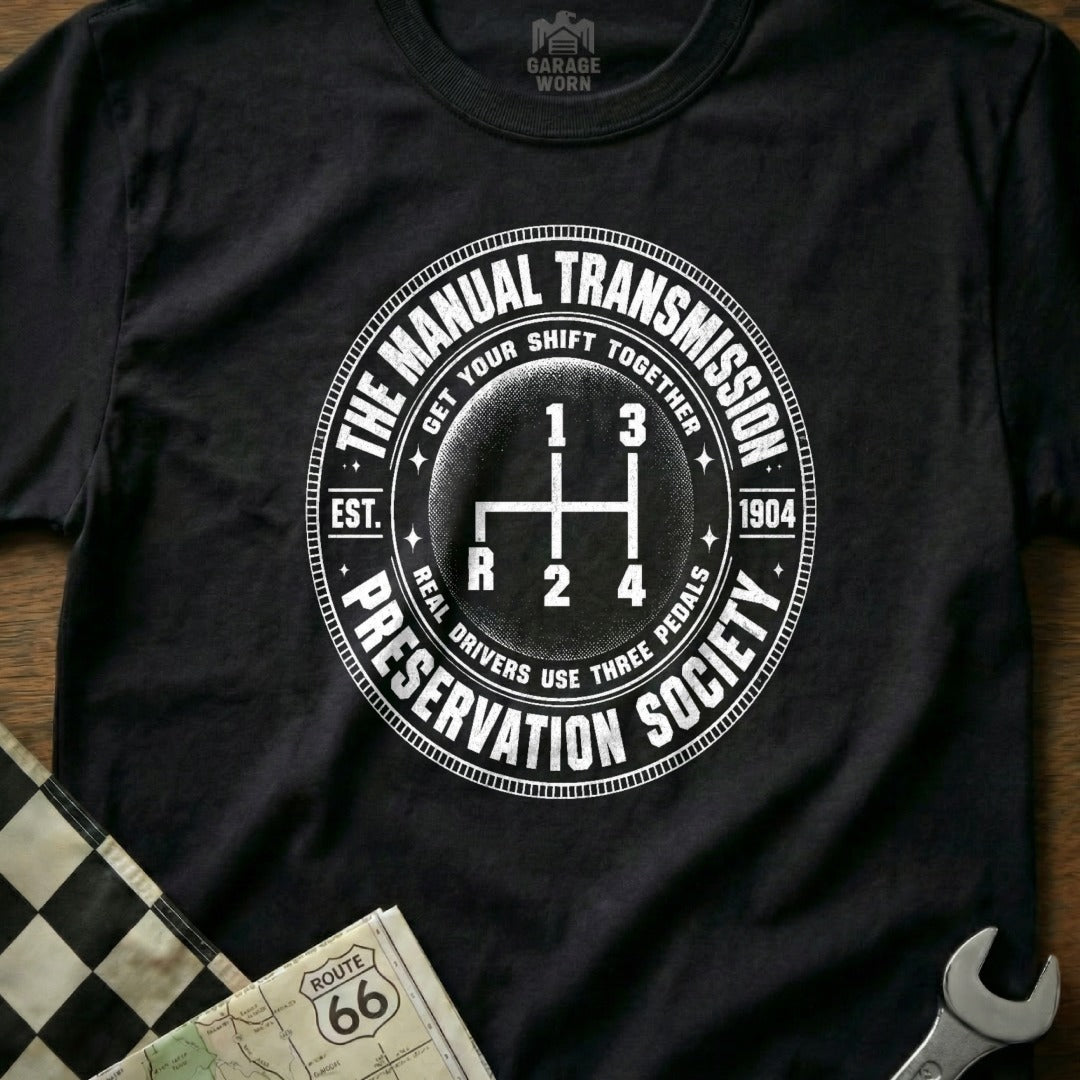 Black t-shirt with circular design: manual transmission graphic, text.