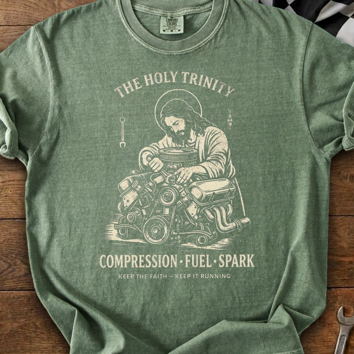 Jesus working on an engine, "The Holy Trinity: Compression, Fuel, Spark."