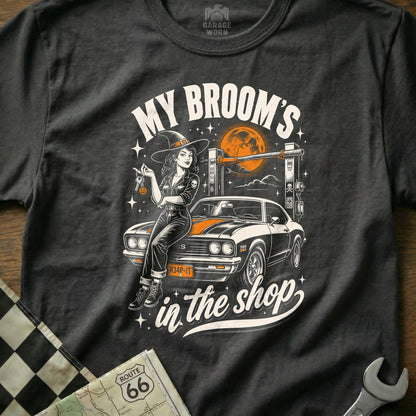Witch with keys sits on car under full moon with text "My Broom's in the shop".