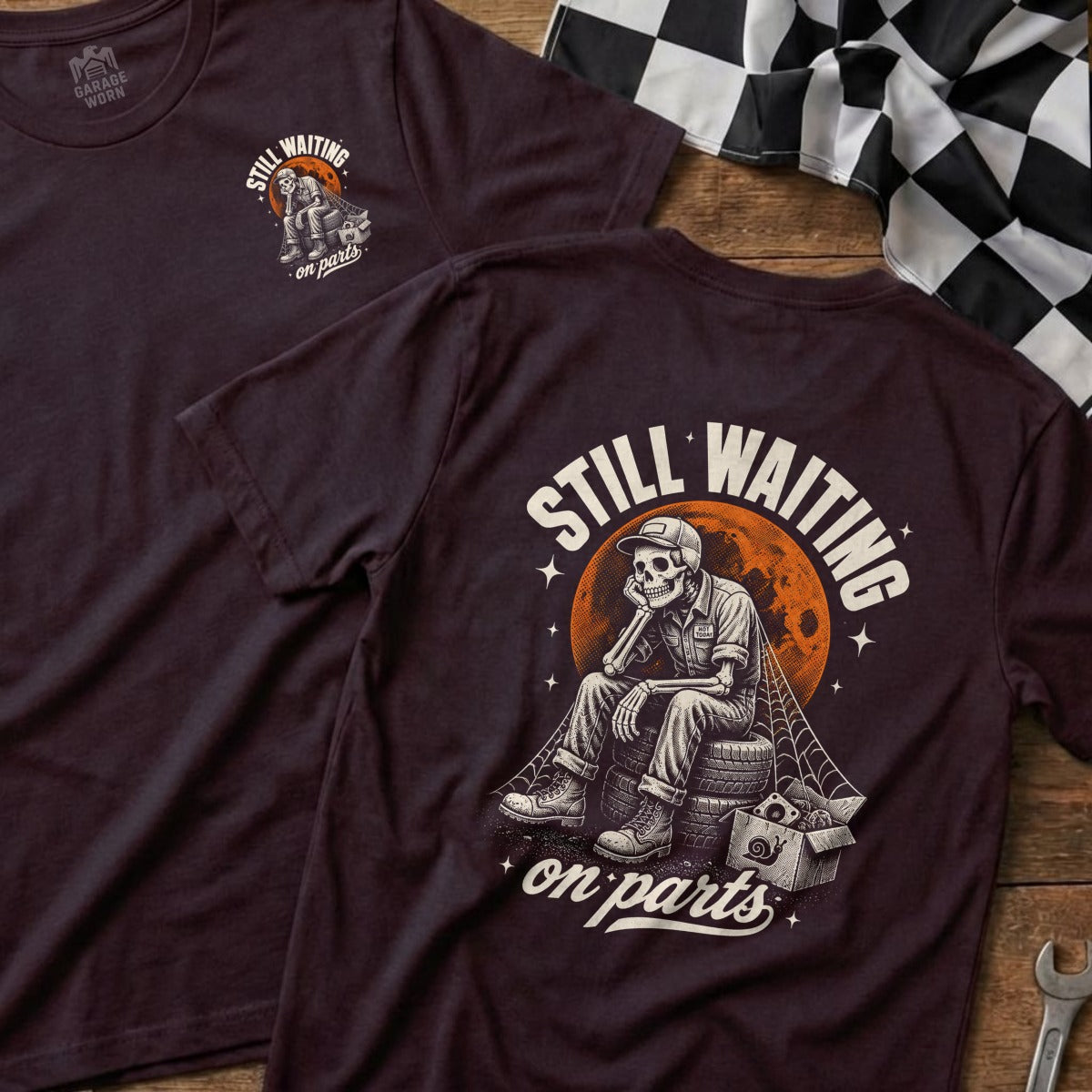 Dark t-shirt with skeleton sitting on tire, text "Still Waiting on Parts."