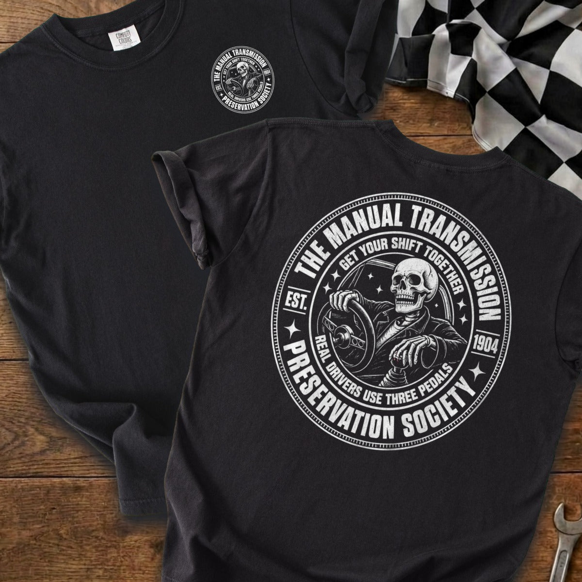 Black t-shirt with circular graphic of skeleton driving and text "The Manual Transmission Preservation Society".