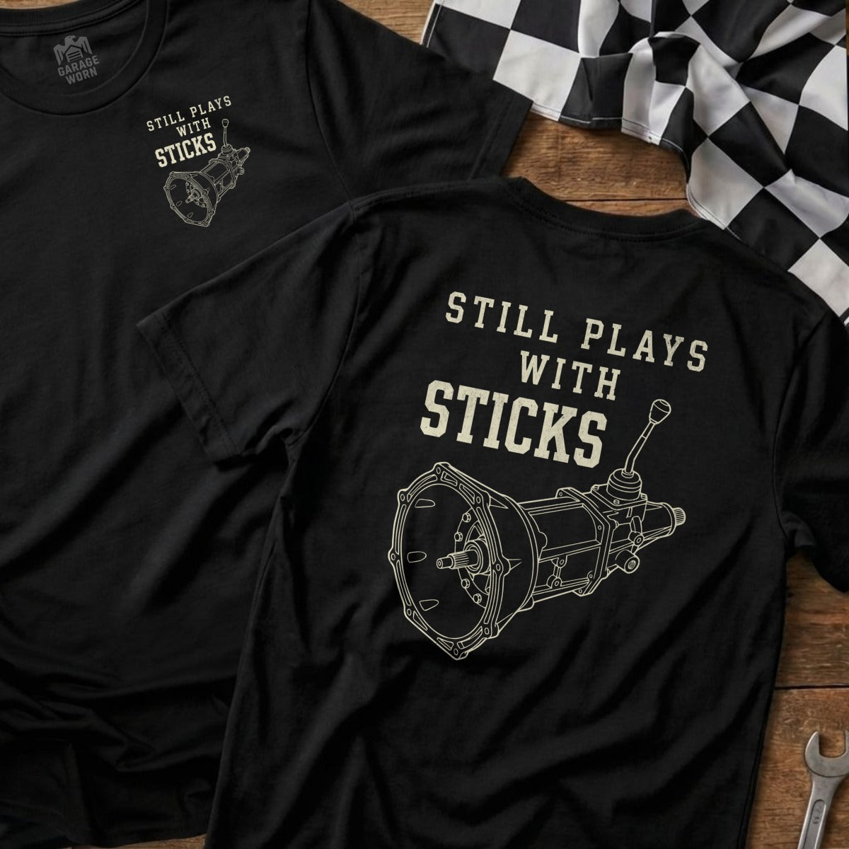 Black t-shirt with "STILL PLAYS WITH STICKS" and a transmission graphic.