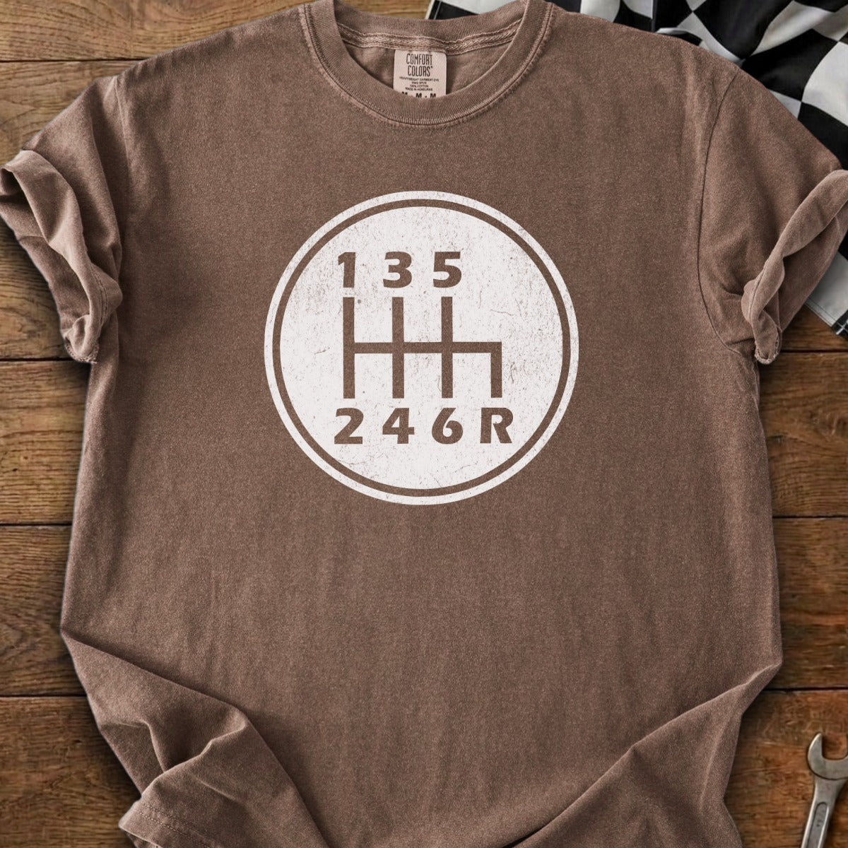 Brown t-shirt with a white vintage manual transmission shift pattern graphic.