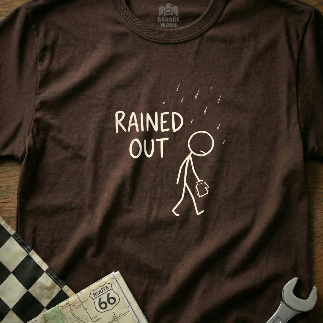 Brown t-shirt with stick figure under rain and text "RAINED OUT".