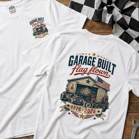 White t-shirt with "Garage Built flag flown" graphic featuring a garage scene with vehicles.