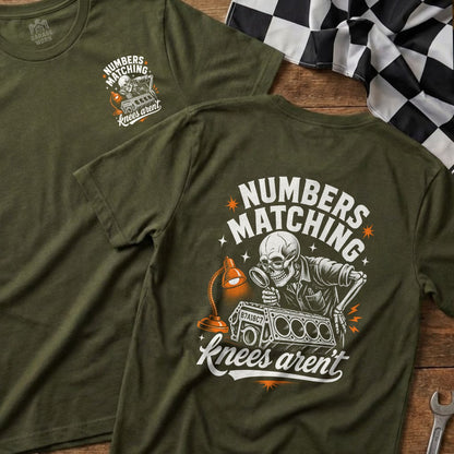 Green t-shirt with graphic of skeleton inspecting an engine block with text.