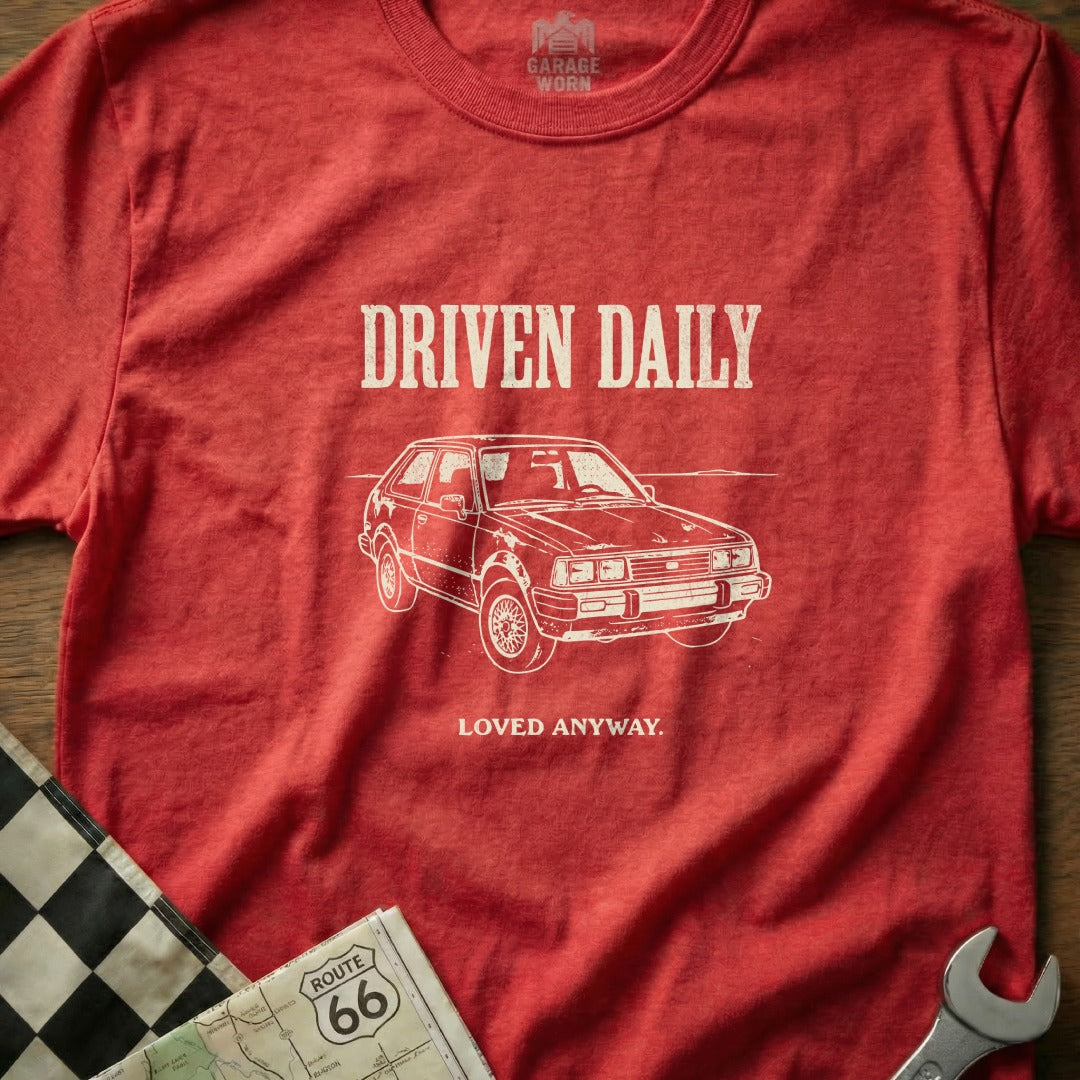 Red t-shirt with "DRIVEN DAILY" and car graphic, "LOVED ANYWAY" text.