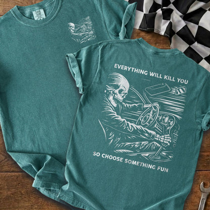 T-shirt graphic of skeleton driving car with text "EVERYTHING WILL KILL YOU SO CHOOSE SOMETHING FUN".