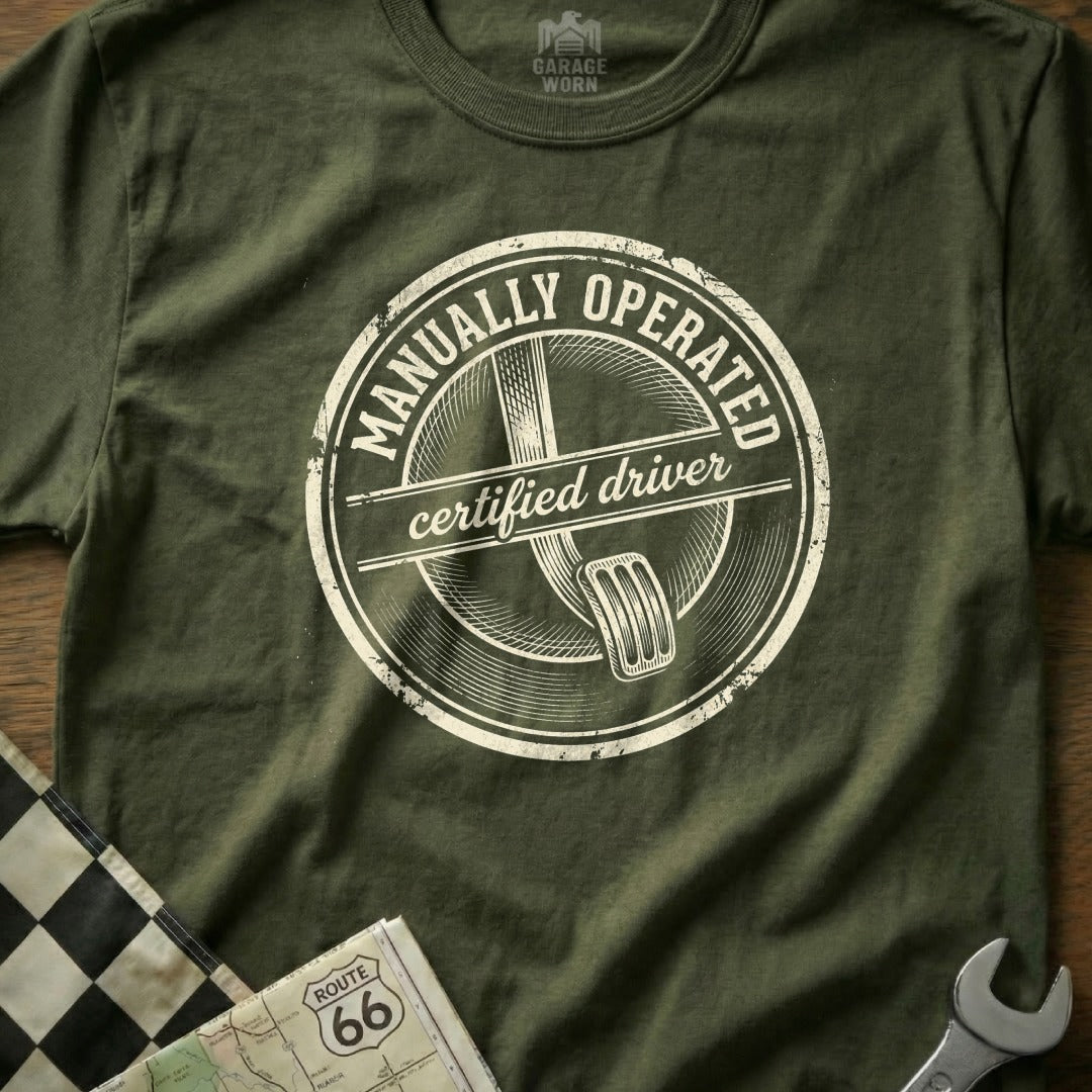T-shirt with "Manually Operated Certified Driver" stamp and clutch pedal graphic.