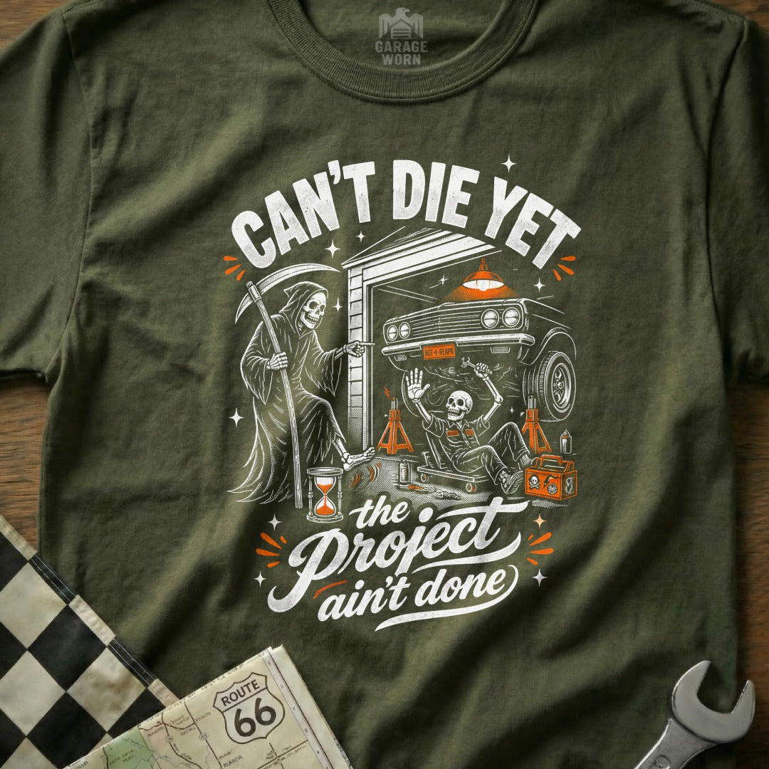 Grim Reaper watches a skeleton working on a car under the text "Can't Die Yet".