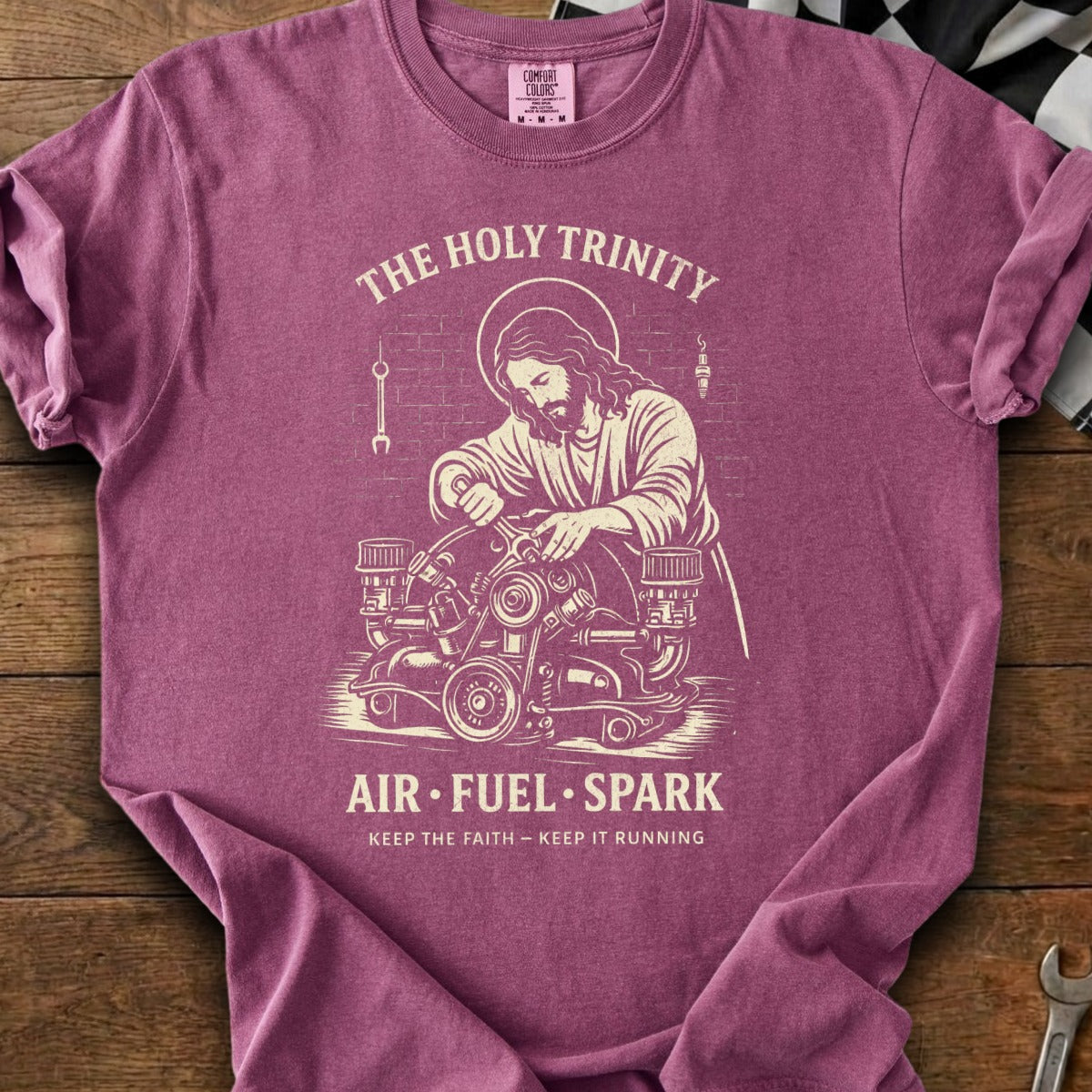 Jesus working on an engine reads "The Holy Trinity Air Fuel Spark".