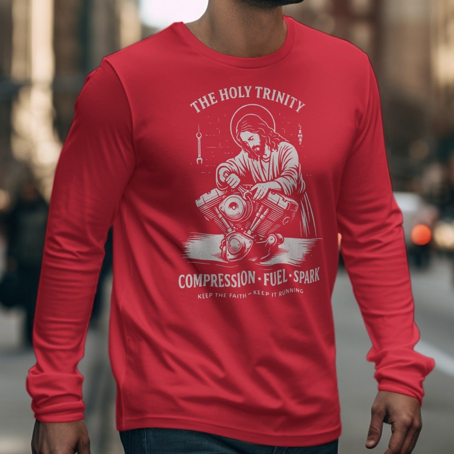 Red long sleeve shirt with "The Holy Trinity," Jesus working on an engine, and "Compression Fuel Spark" text.