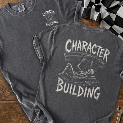 Dark gray t-shirt with a skeleton working on a car, the words "CHARACTER BUILDING" above and below.