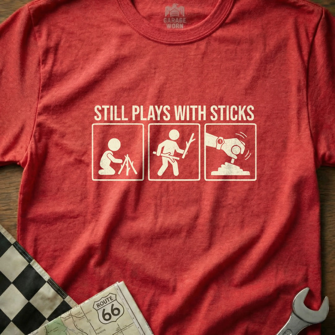 Red t-shirt with "STILL PLAYS WITH STICKS" and three stick figure graphics.