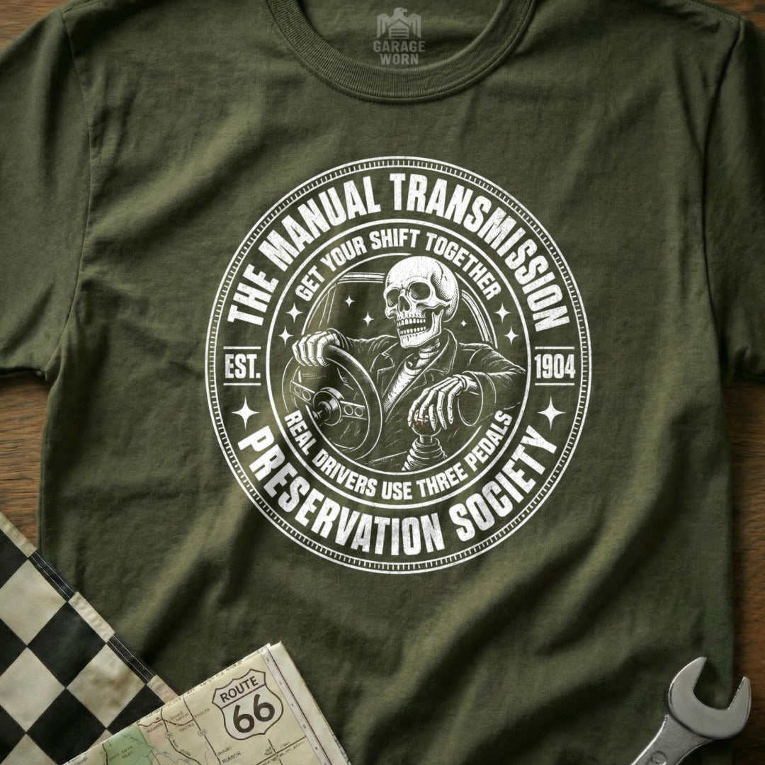 T-shirt graphic with skeleton driving, "The Manual Transmission Preservation Society" text.