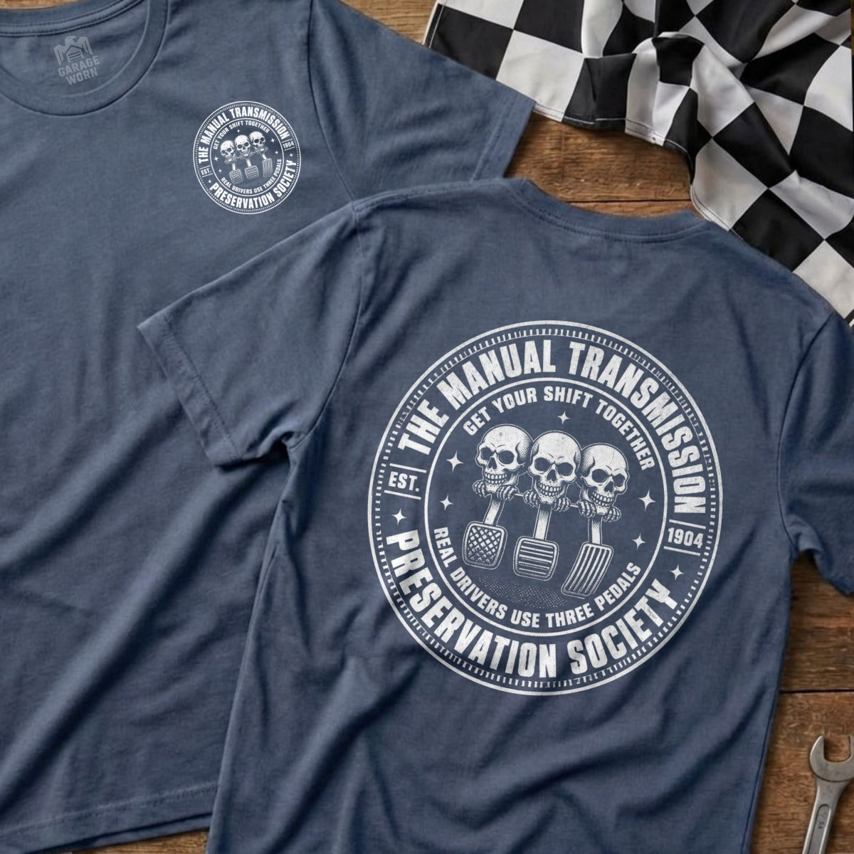 Blue t-shirt with "The Manual Transmission Preservation Society" graphic featuring skulls and pedals.