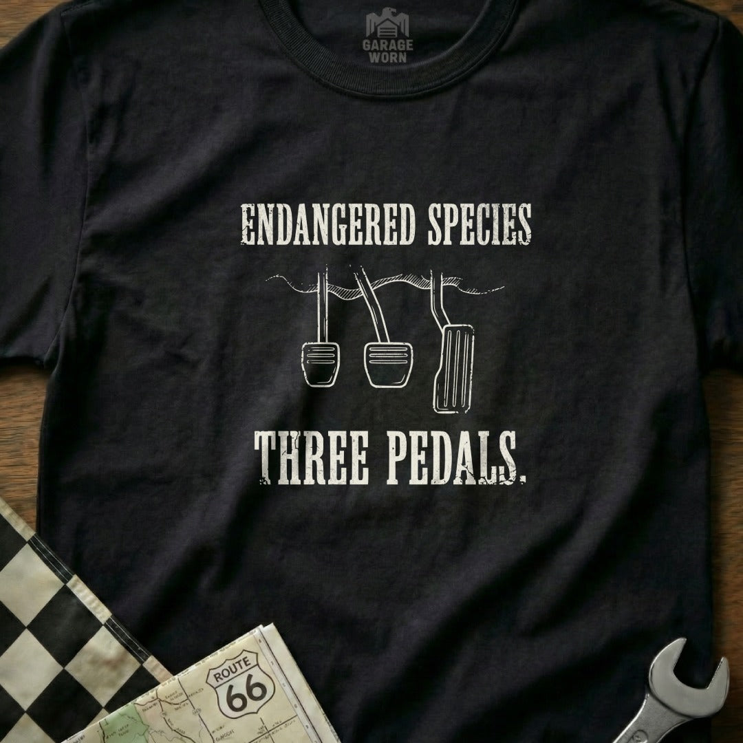 Black t-shirt with "Endangered Species Three Pedals" text and car pedals graphic.