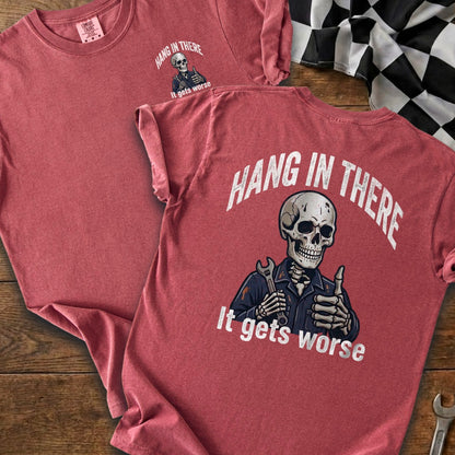 Red t-shirt with a skeleton holding a wrench, giving a thumbs up. "Hang in there, it gets worse."