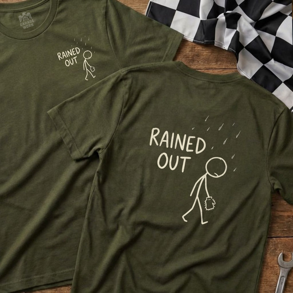 Olive green t-shirt with stick figure running in rain, "RAINED OUT" text.