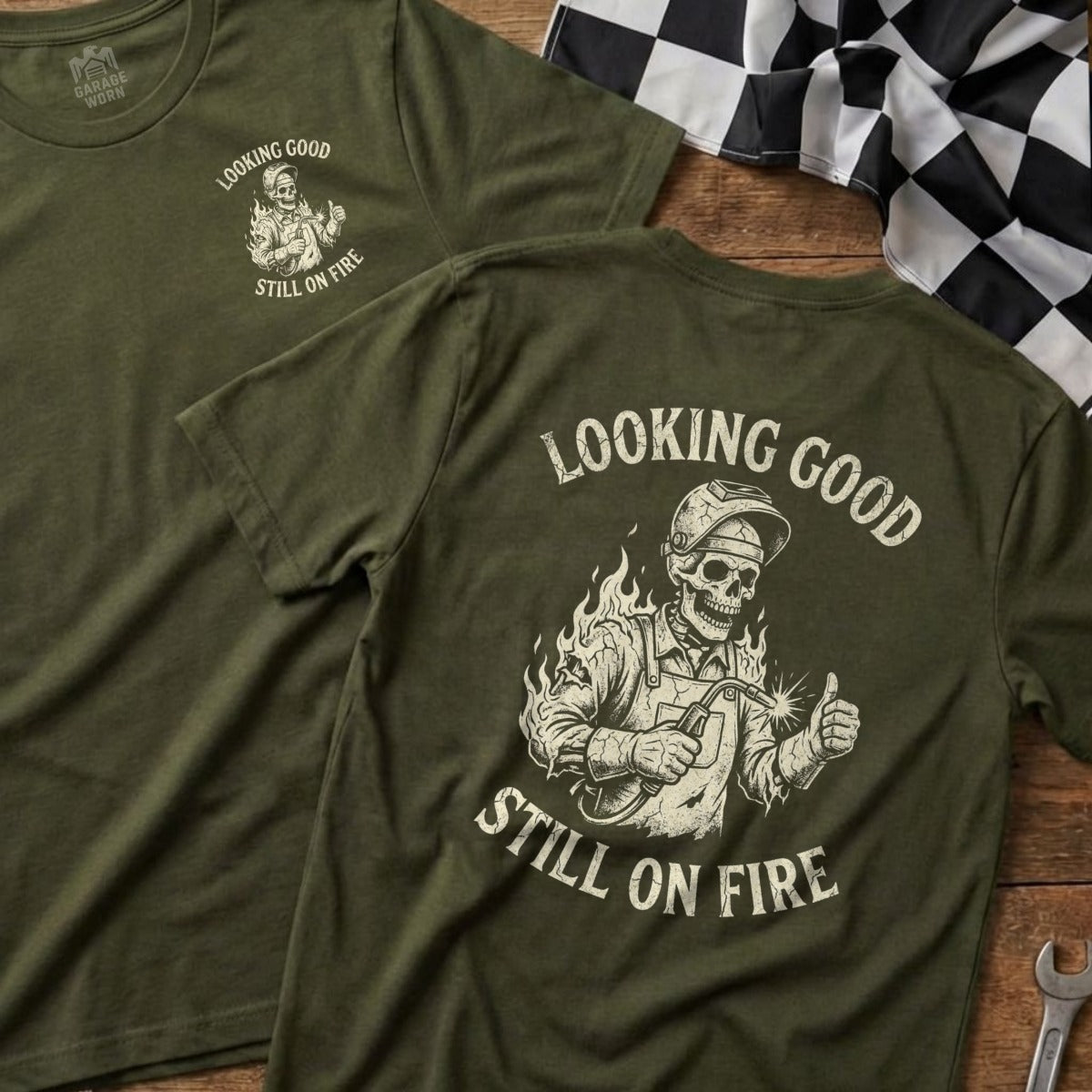 Green t-shirt with skull welder, thumbs up, and text "Looking Good Still on Fire".