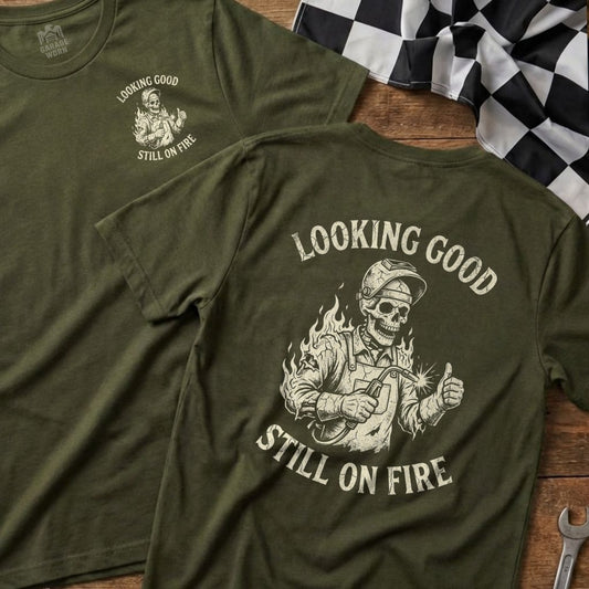 Green t-shirt with skull welder, thumbs up, and text "Looking Good Still on Fire".