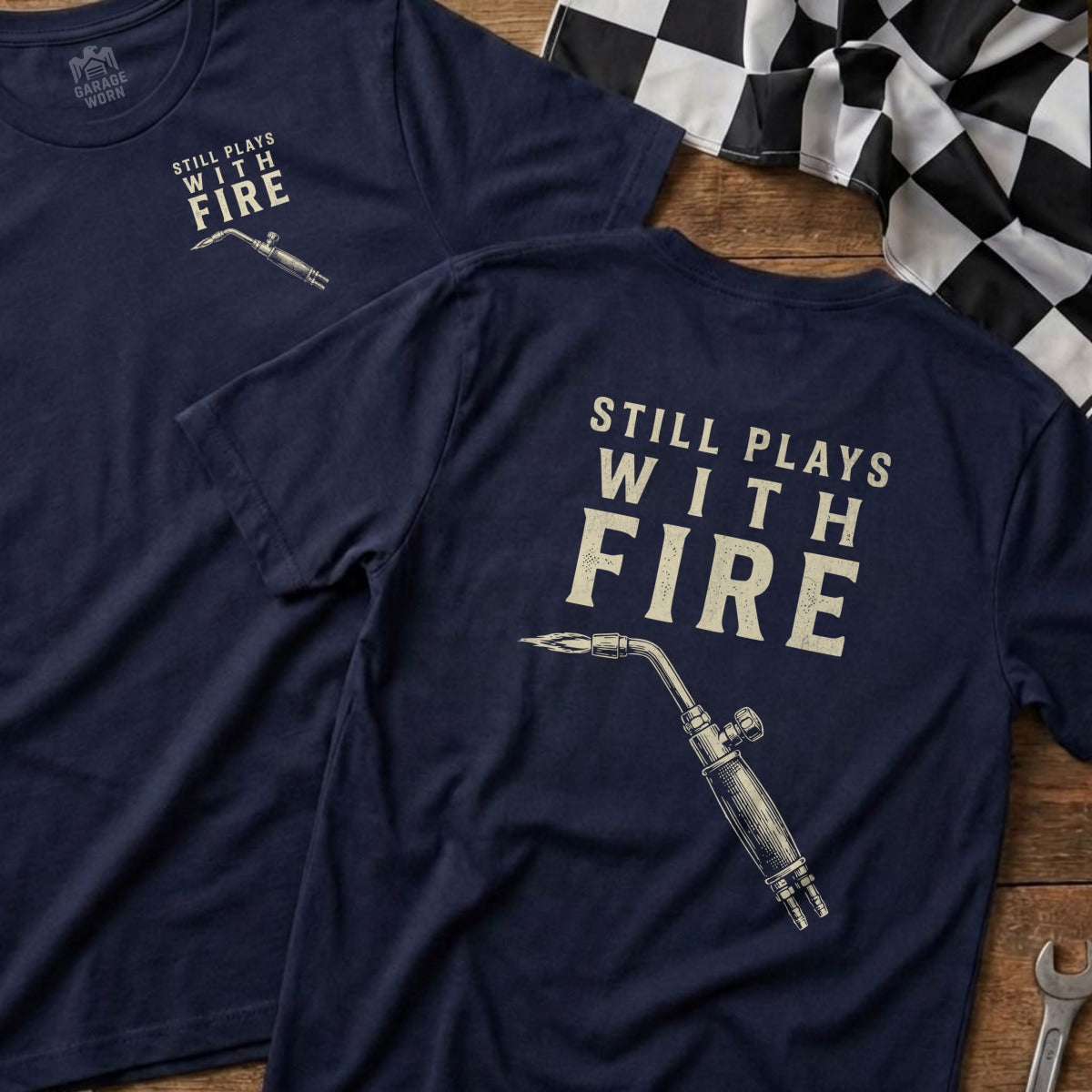 Navy t-shirt with "Still Plays With Fire" and a welding torch graphic.