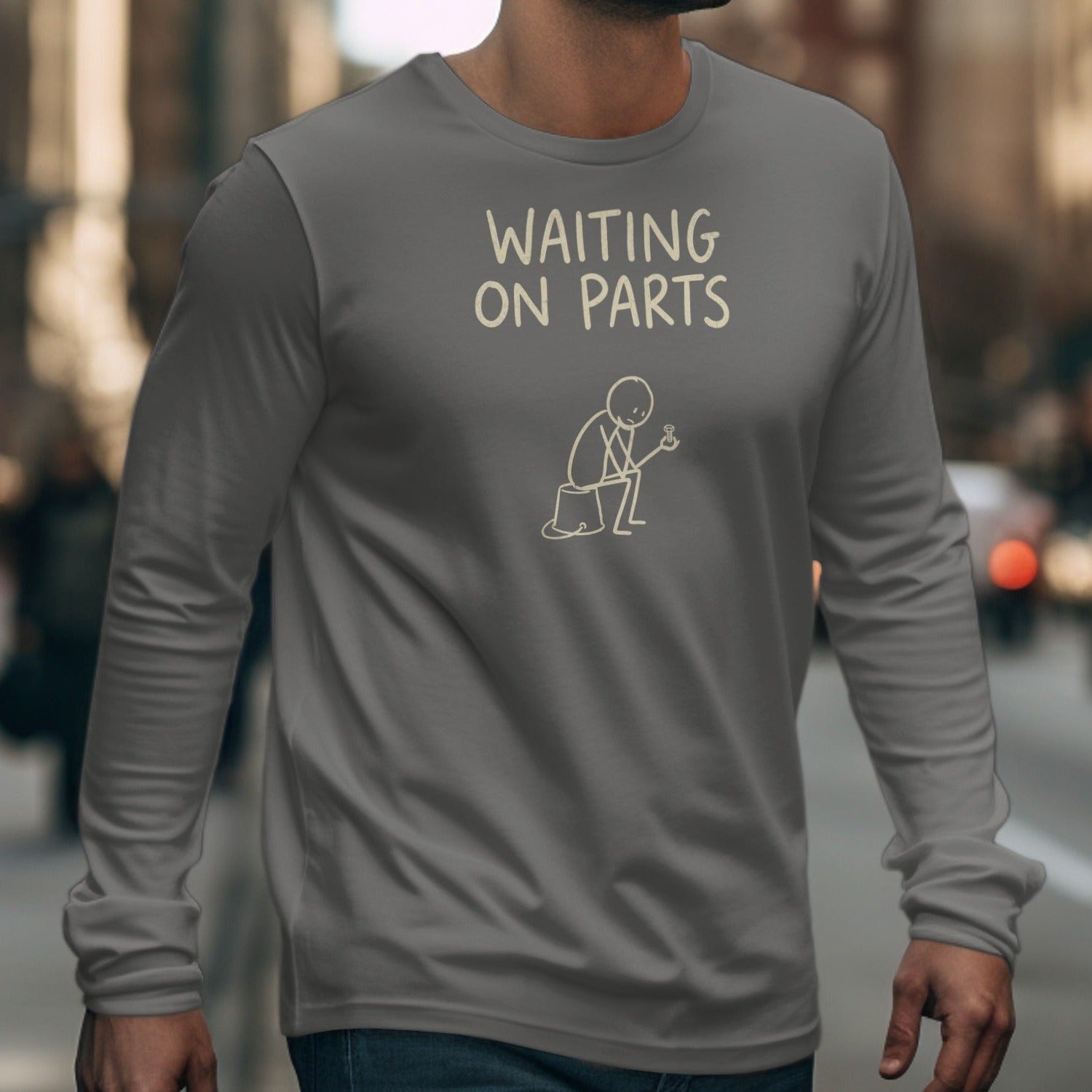 Grey long sleeve shirt with text "WAITING ON PARTS" and stick figure artwork.